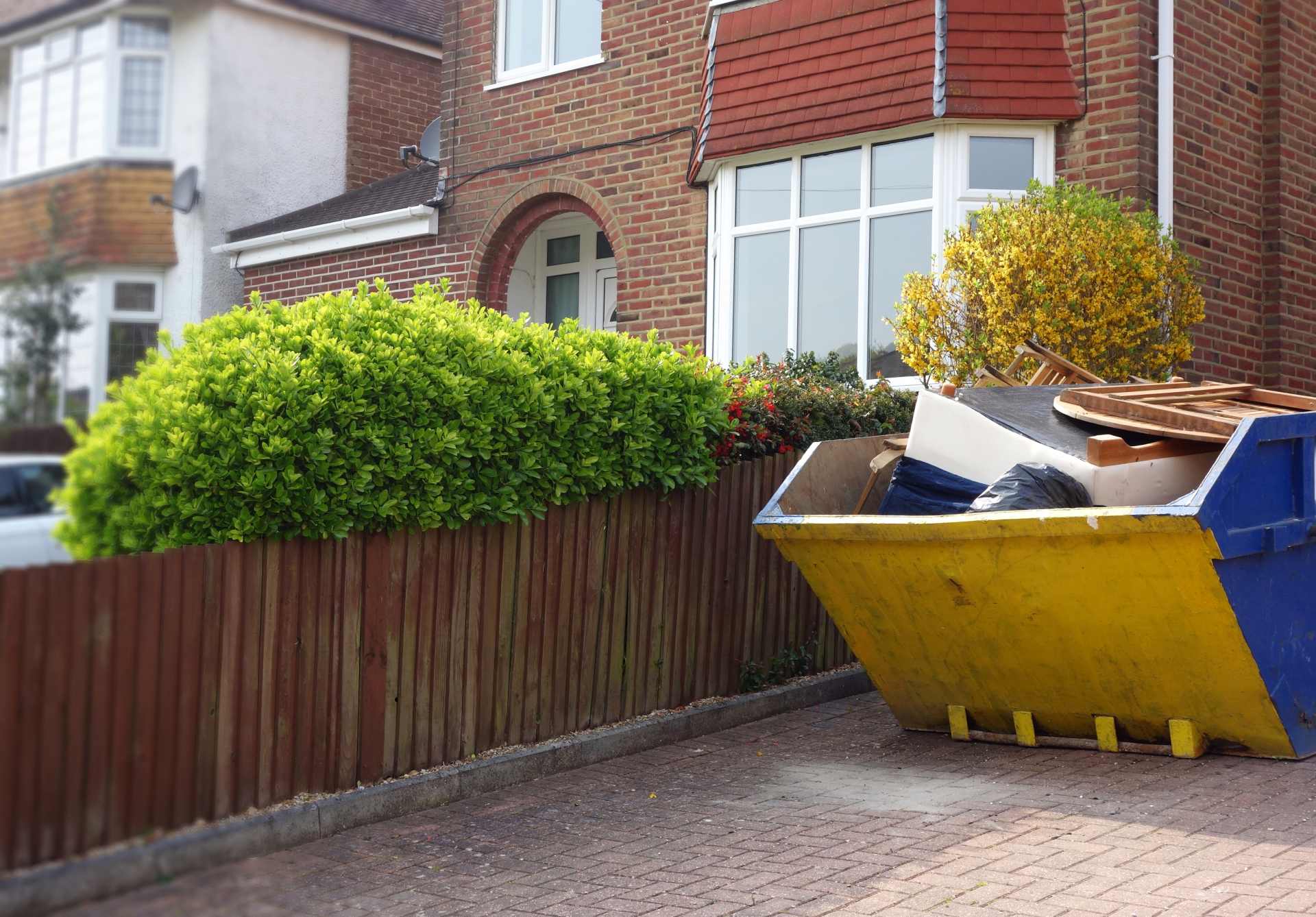 Yellow skip in driveway of red-brick house