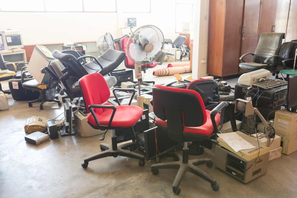 Abandoned office with old chairs, electronics, and fans.