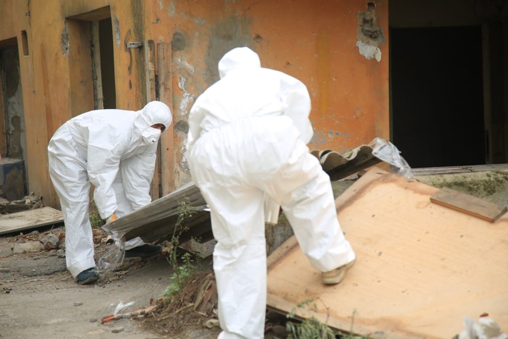 Workers in hazmat suits removing hazardous materials.