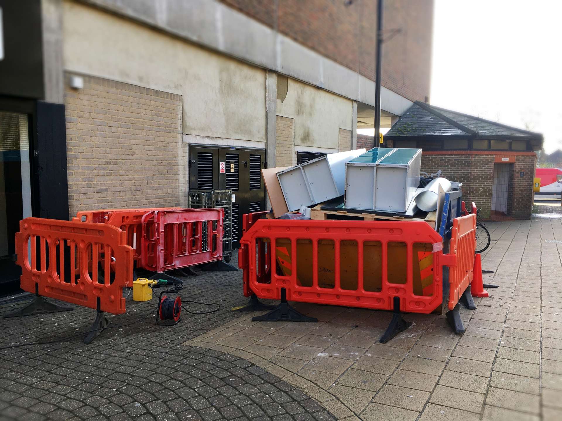 Red barriers around piled metal cabinets outdoors.